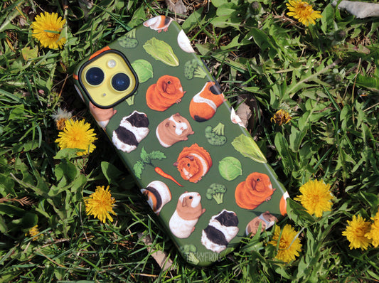 The guinea pig phone case placed near dandelions.