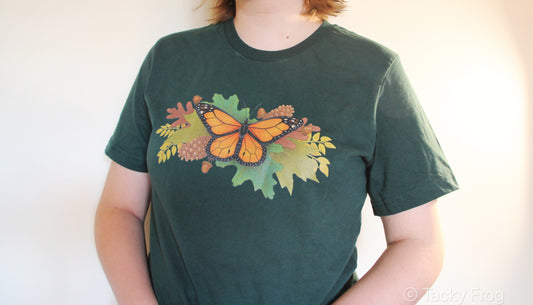 A green t-shirt with a butterfly and autumn leaves on it.