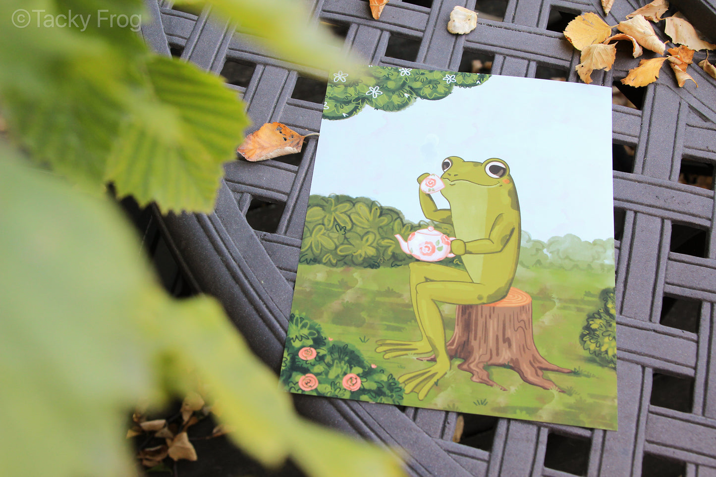 A view of the tea drinking frog art print from behind from leaves. This image shows the matte finish well.