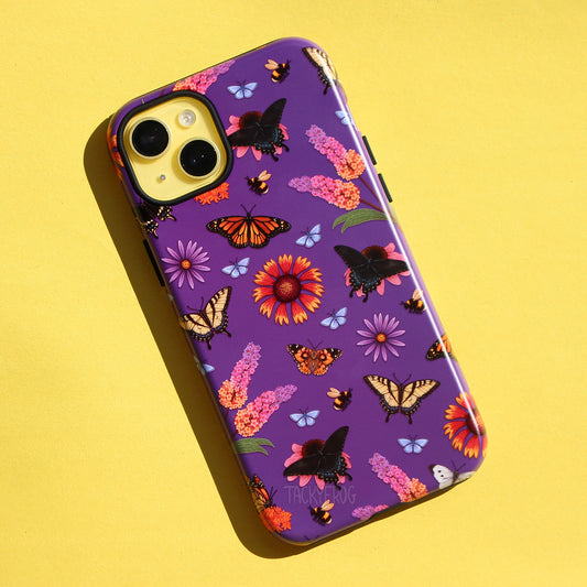 A dark purple phone case featuring a pattern of various butterflies and flowers, including but not limited to the monarch butterfly, swallowtail butterflies, and butterfly bushes.