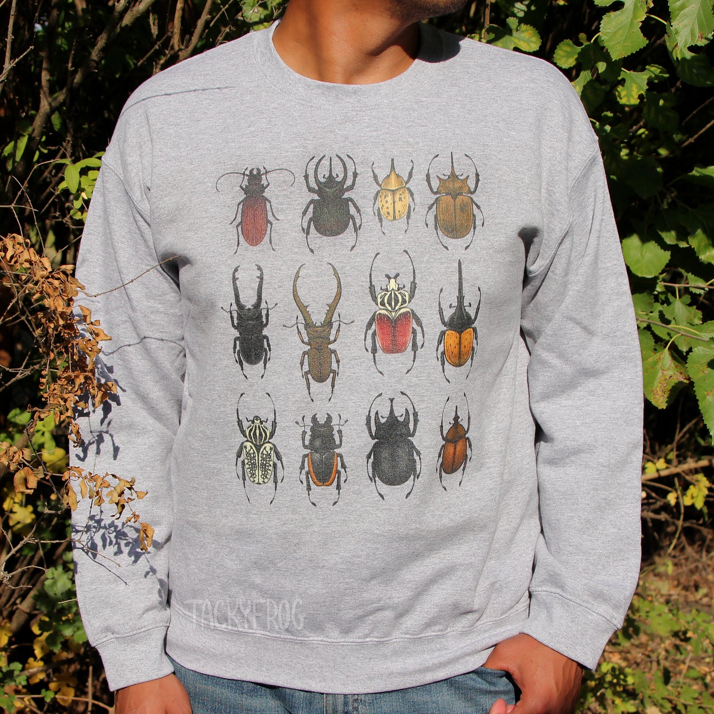 A man wearing a sweatshirt featuring a design of twelve different beetles, including stag beetles, Goliath beetles, and Hercules beetles.