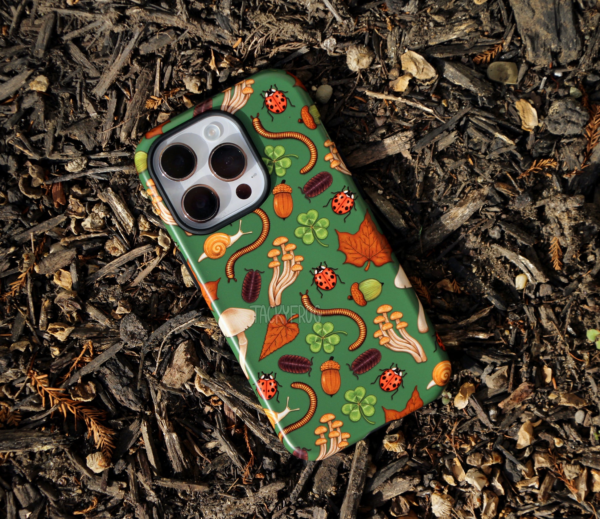 The dark green backyard nature-inspired phone case placed on top of decaying mulch.