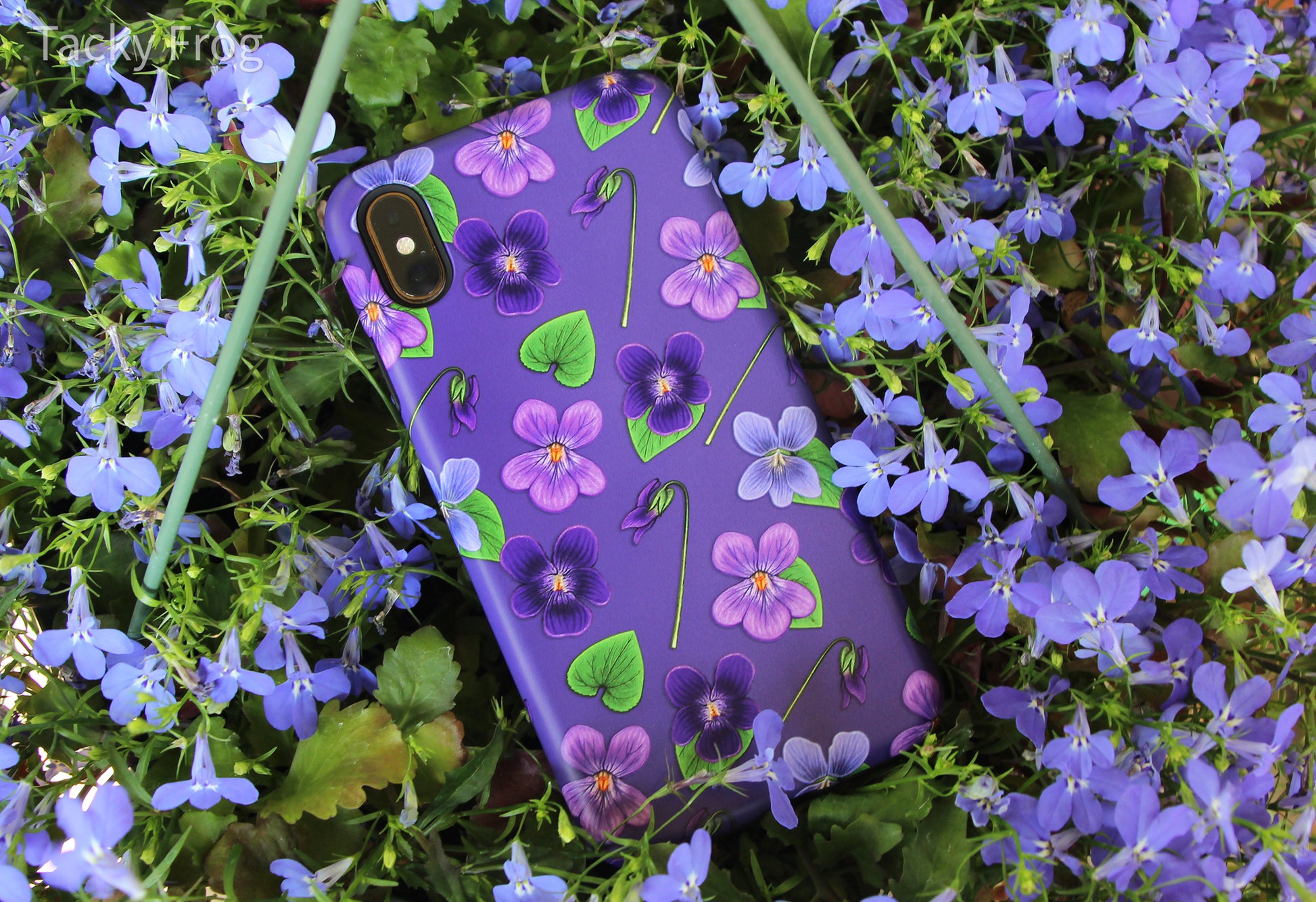 The violet phone case placed in a bed of purple flowers. This picture was taken in a shaded area to show the phone case in another lighting level.