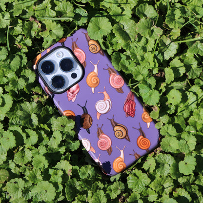 The snail patterned phone case surrounded by vegetation.