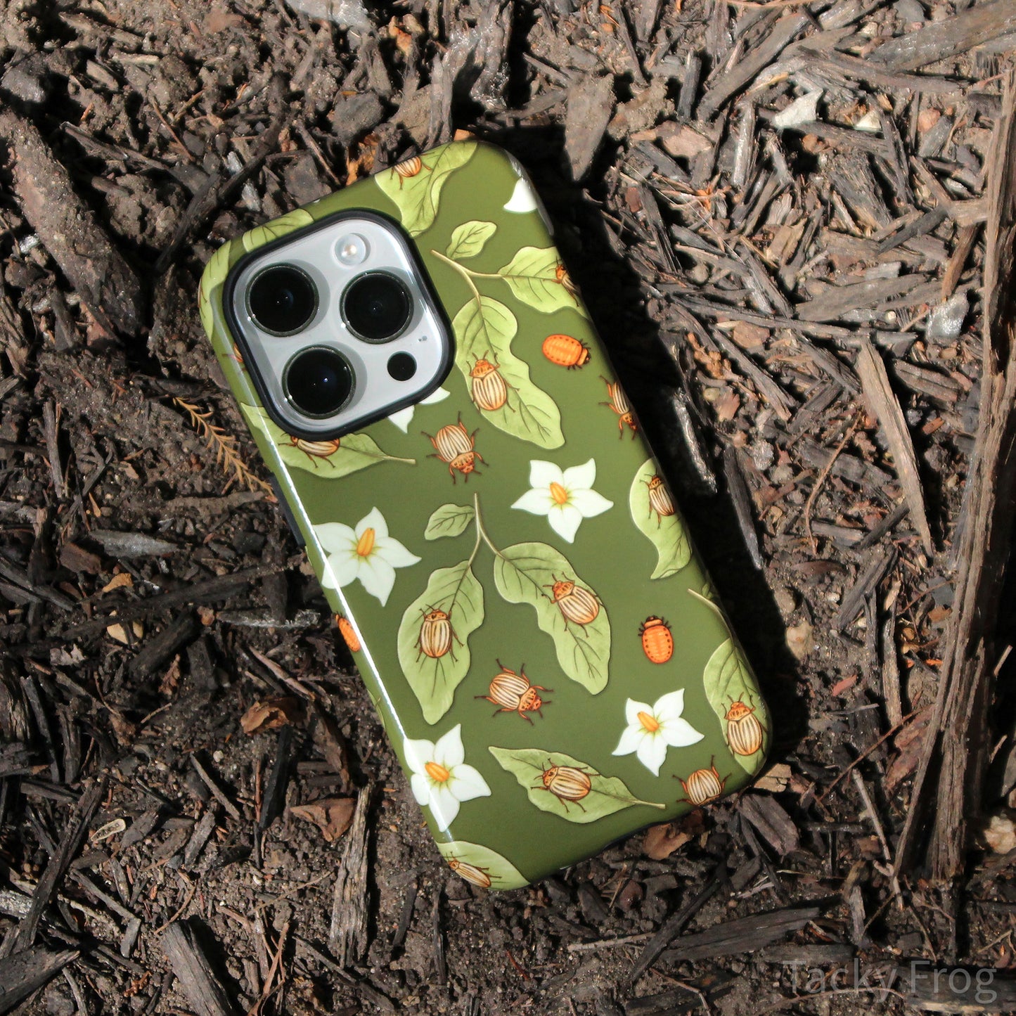 The potato beetle phone case placed in some mulch.