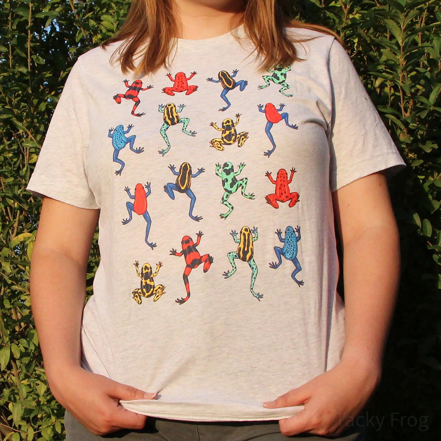 A woman wearing the colorful dart frog t-shirt. The shirt features eight different dart frogs with each dart frog repeating twice. The color variant shown is "ash".