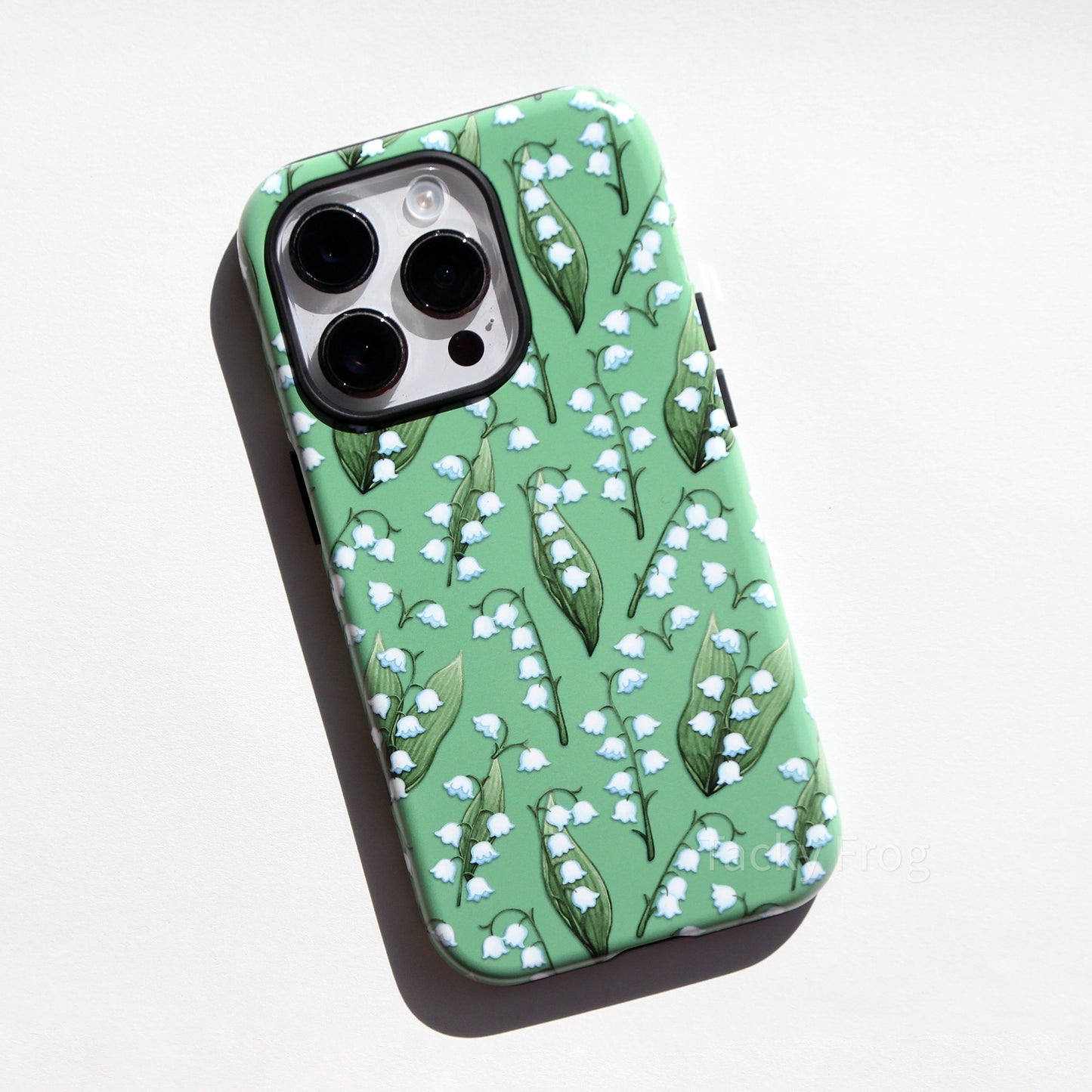 A green phone case featuring a pattern of lilies of the valley and leaves.