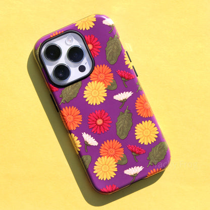 A phone case featuring a pattern of green leaves and yellow, orange, white, and magenta Gerbera daisies against a purple background.