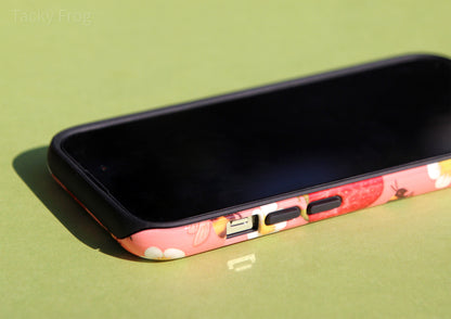 The strawberries and bees phone case shown screen-side up. The black inner layer is visible around the camera, buttons, speaker, and charging port.