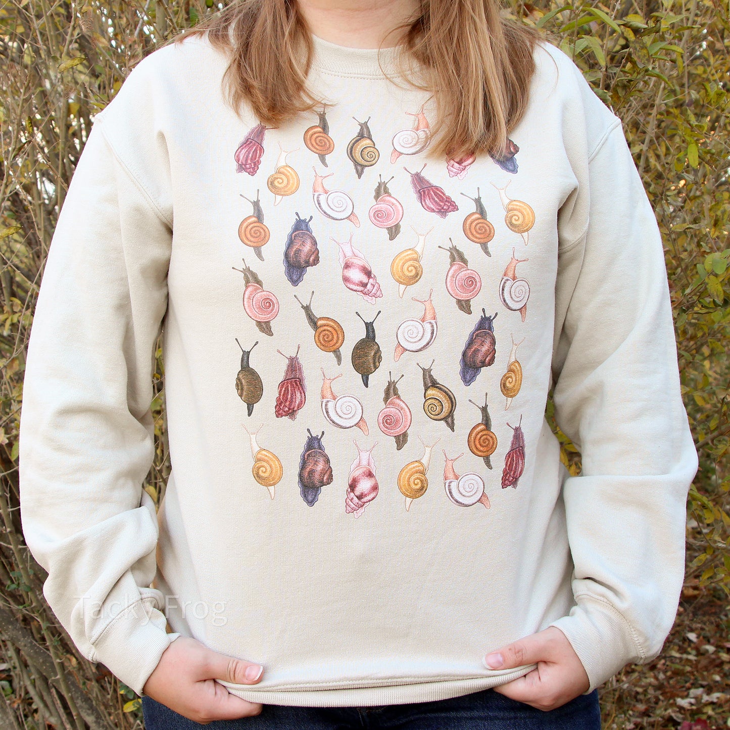 A woman wearing the sand-colored snails sweatshirt in different lighting.