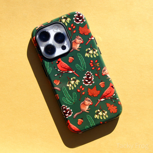 A green phone case featuring a pattern of various winter nature walk-inspired elements, including cardinals, chipmunks, rose hip, snowy pinecones, pine leaves, and more.