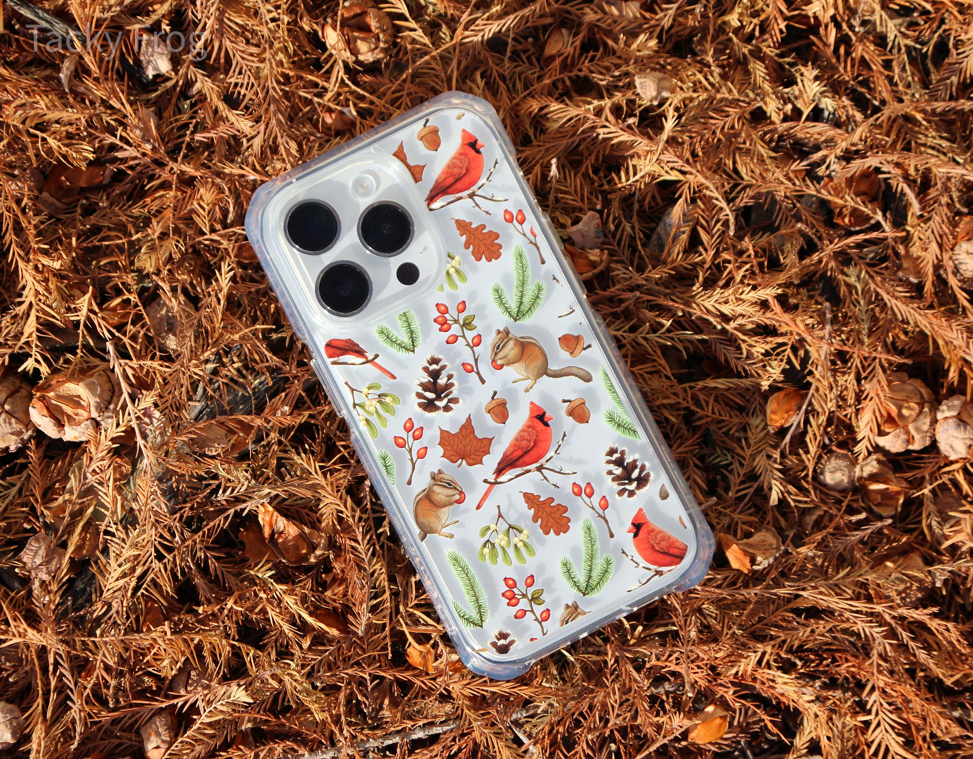 The winter nature-inspired phone case placed in a pile of dead cypress leaves. It is shown on a light-colored phone.