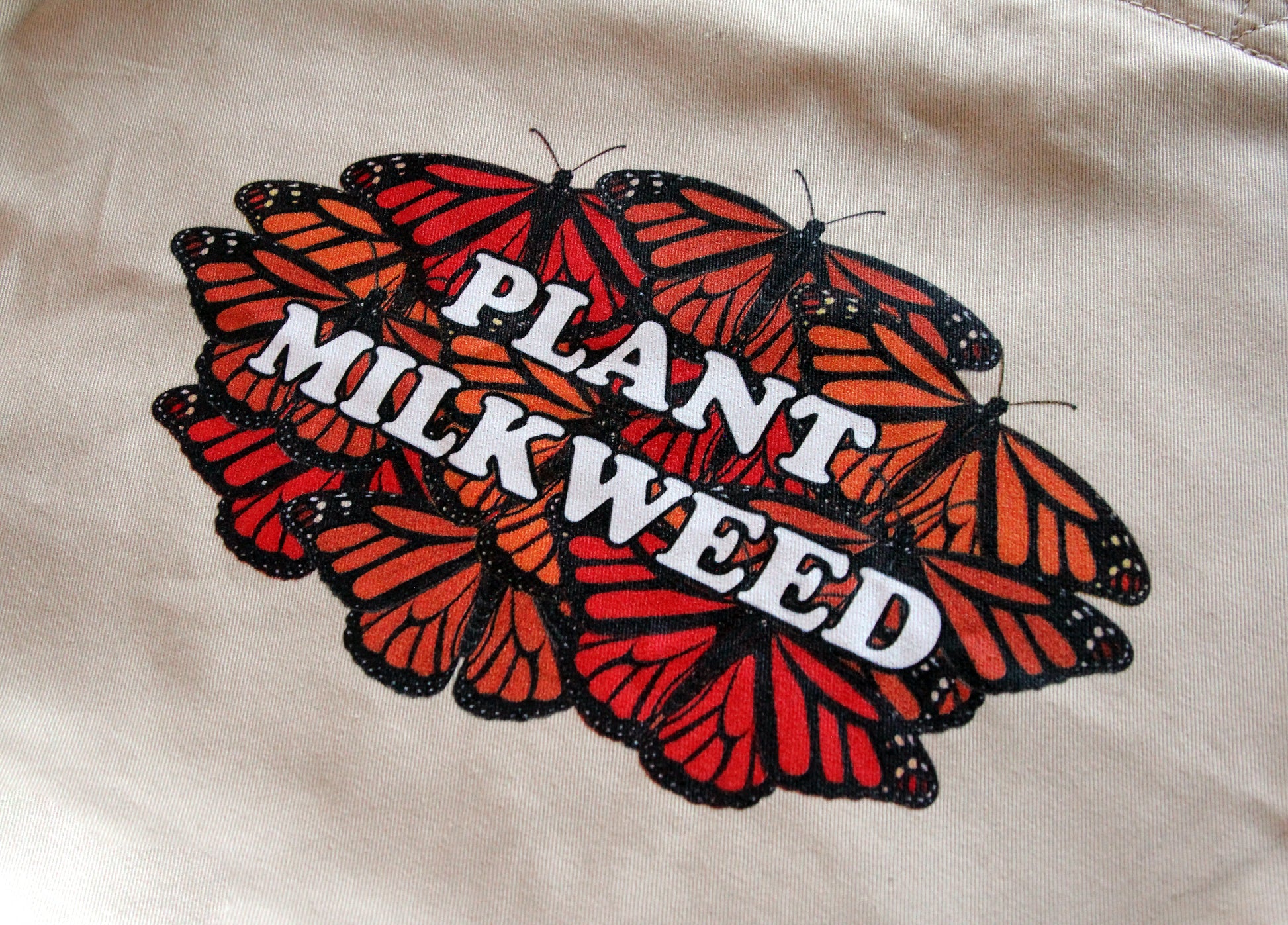 A closeup of the print on the plant milkweed tote bag. The print is only on one side of the tote bag.