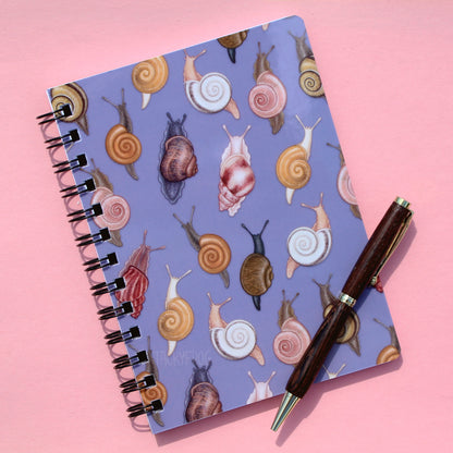 A muted purple notebook featuring a pattern of various snails. The pen is not included.