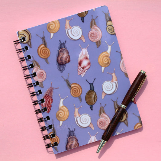 A muted purple notebook featuring a pattern of various snails. The pen is not included.