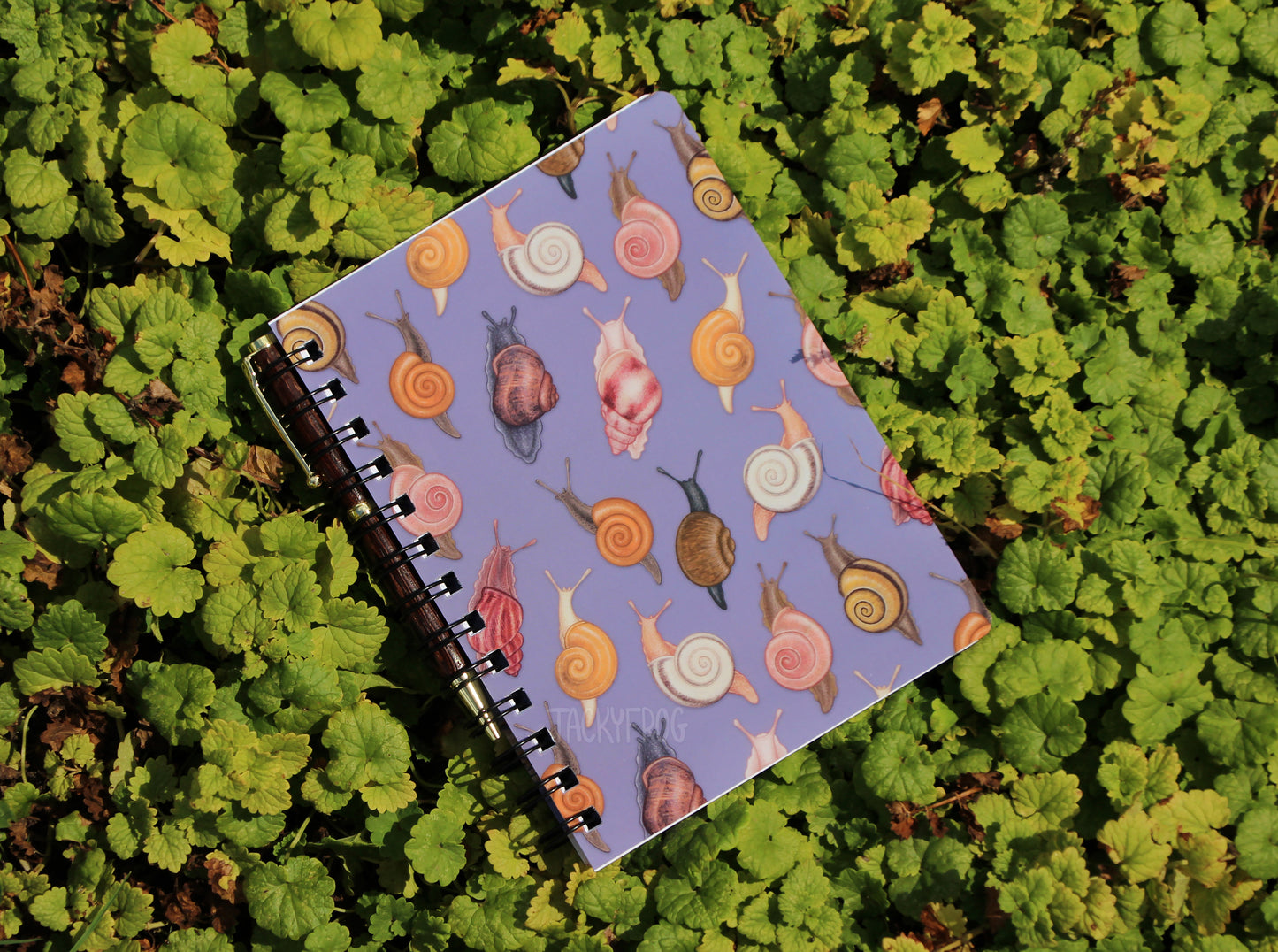 The snail notebook placed on green vegetation.