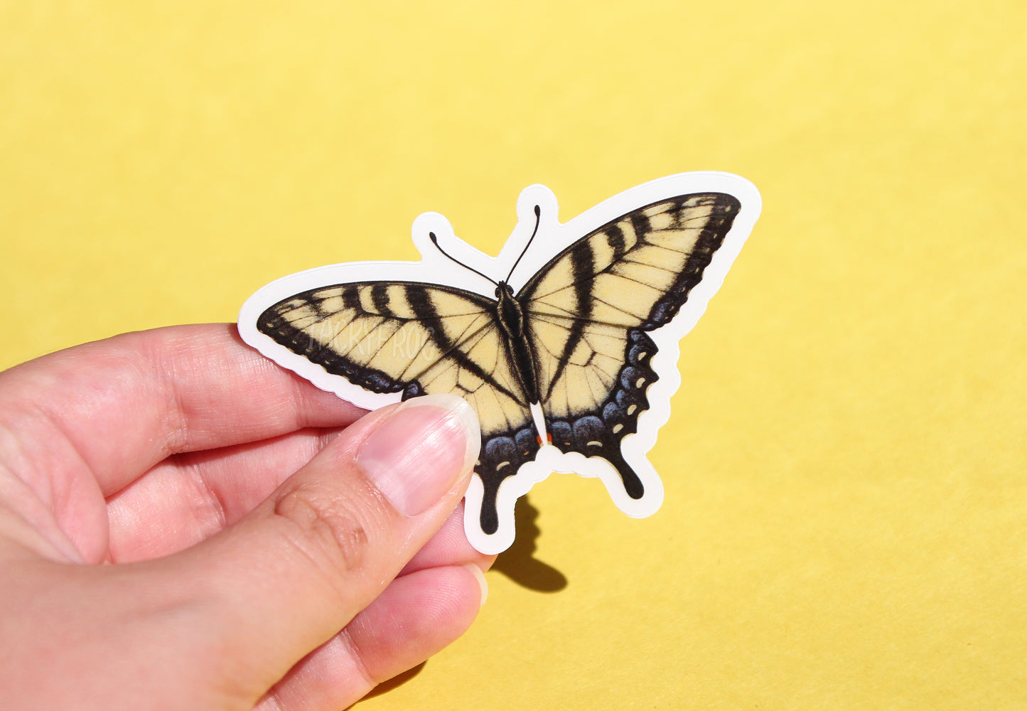 The yellow swallowtail butterfly sticker with the white paper backing still on.