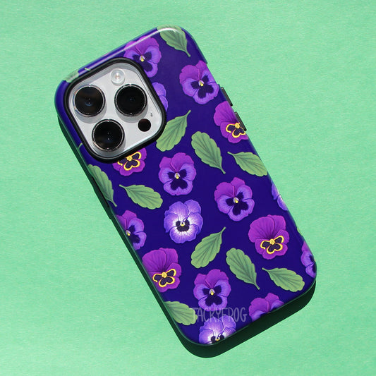 A mockup of a dark purple phone case featuring a pattern of purple pansies and leaves. The case has an inner black layer that is visible around openings and buttons.