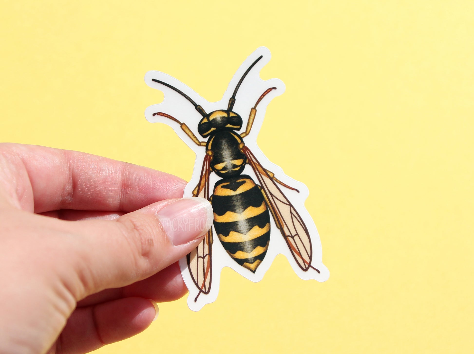 A clear vinyl sticker of a yellow jacket wasp with the white paper backing still on.