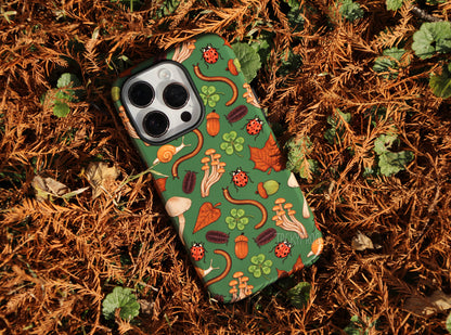 The dark green backyard nature-inspired phone case placed in a pile of dead cypress leaves.