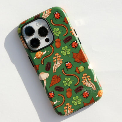 A dark green phone case featuring some common nature objects, specifically dead leaves, mushrooms, acorns, ladybugs, pillbug, millipedes, clovers and snails.