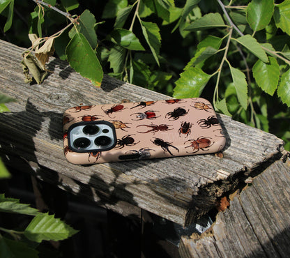 The beetle phone case placed on a wooden railing next to tree branches.
