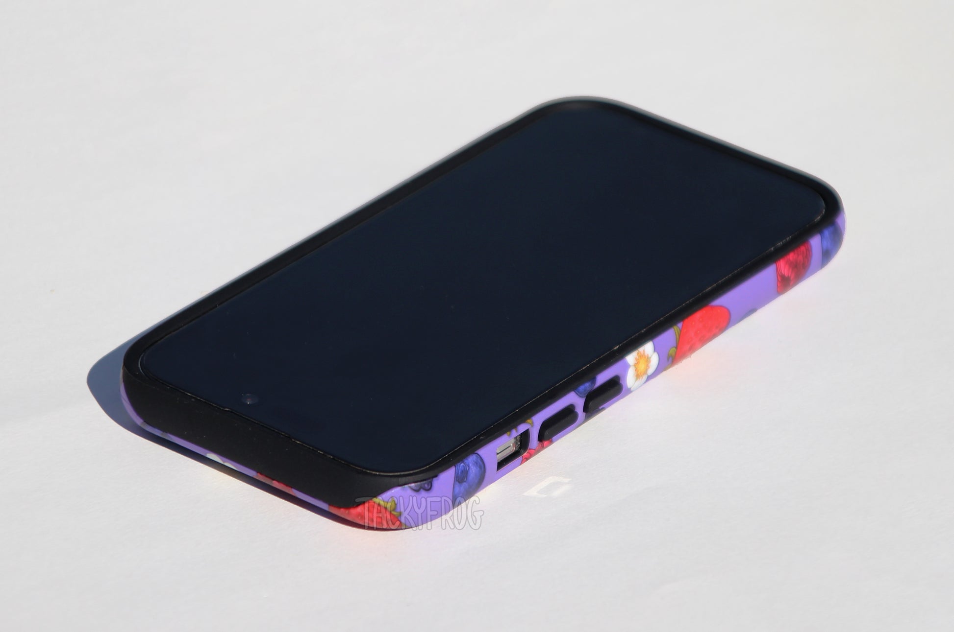 The purple berry-patterned phone case shown screen-side up.