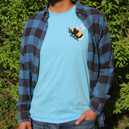The bumble bee embroidered shirt, shown in the color "ocean blue" worn under a blue and black flannel. The flannel is not included.