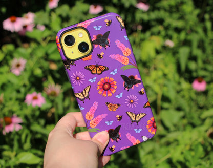 The butterfly garden-inspired phone case held in front of a coneflower garden.