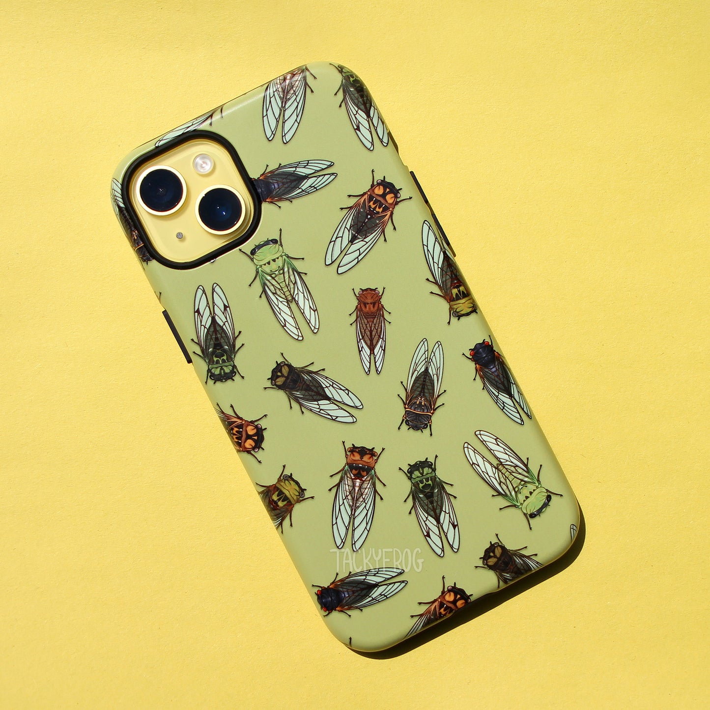 A light green phone case featuring a pattern of various cicadas. It is shown on a yellow phone.