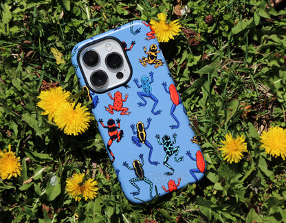 The dart frog blue phone case placed in the grass with dandelions.