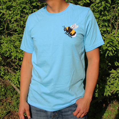 Person wearing an ocean-blue t-shirt with an embroidered bee design on it