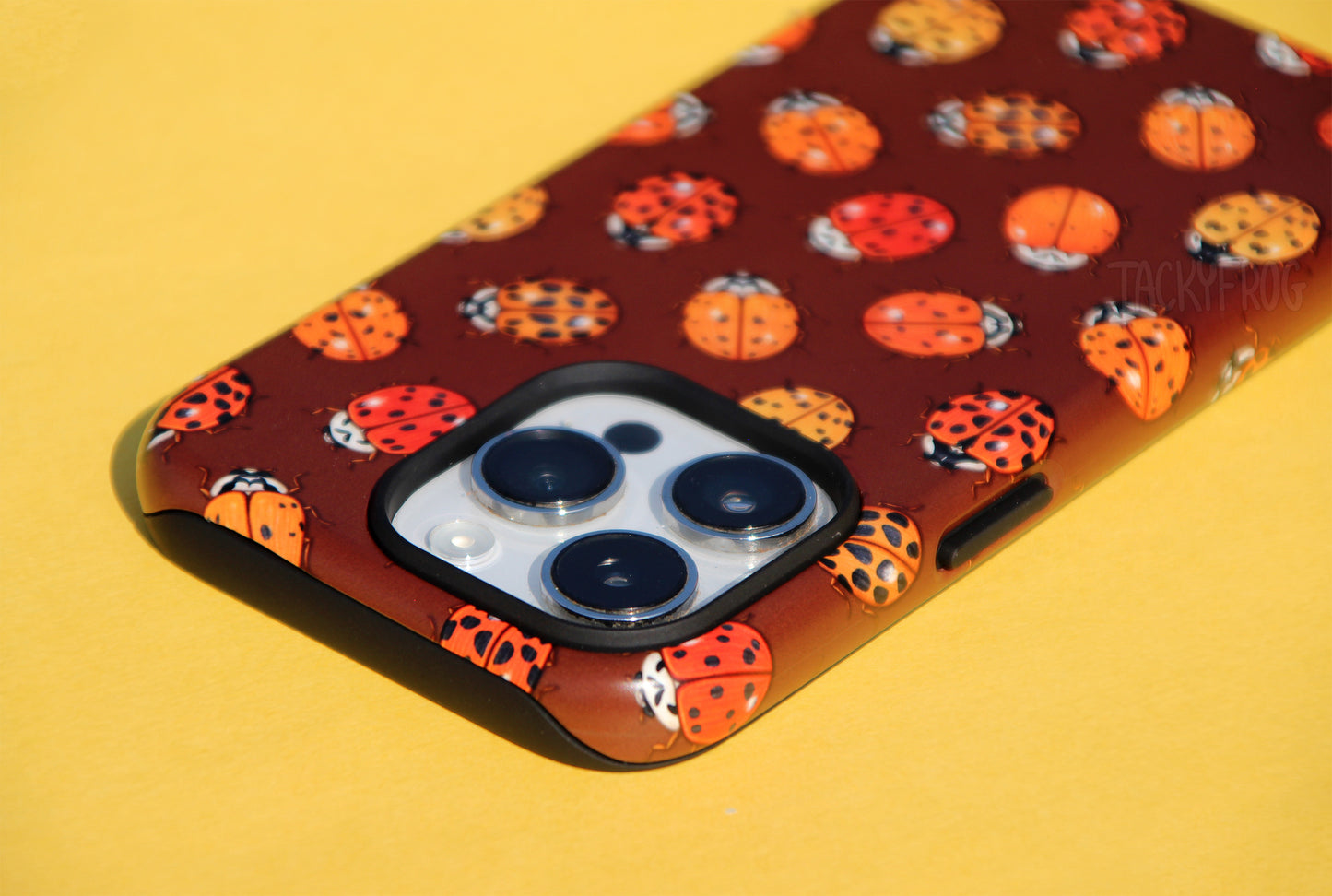 An angled view of the ladybug-patterned phone case. The inner layer of the case is solid black. It is visible around openings and buttons.