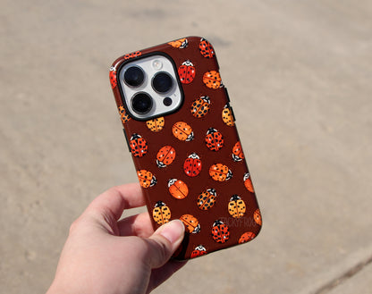 The ladybug phone case held above concrete.