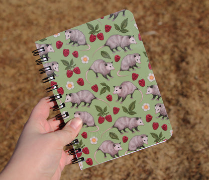 The opossums notebook held over dead grass.
