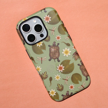 A light muted green phone case featuring a pattern of wildlife that can be found near ponds, including dragonflies, painted turtles, tadpoles, lily pads, and frogs.