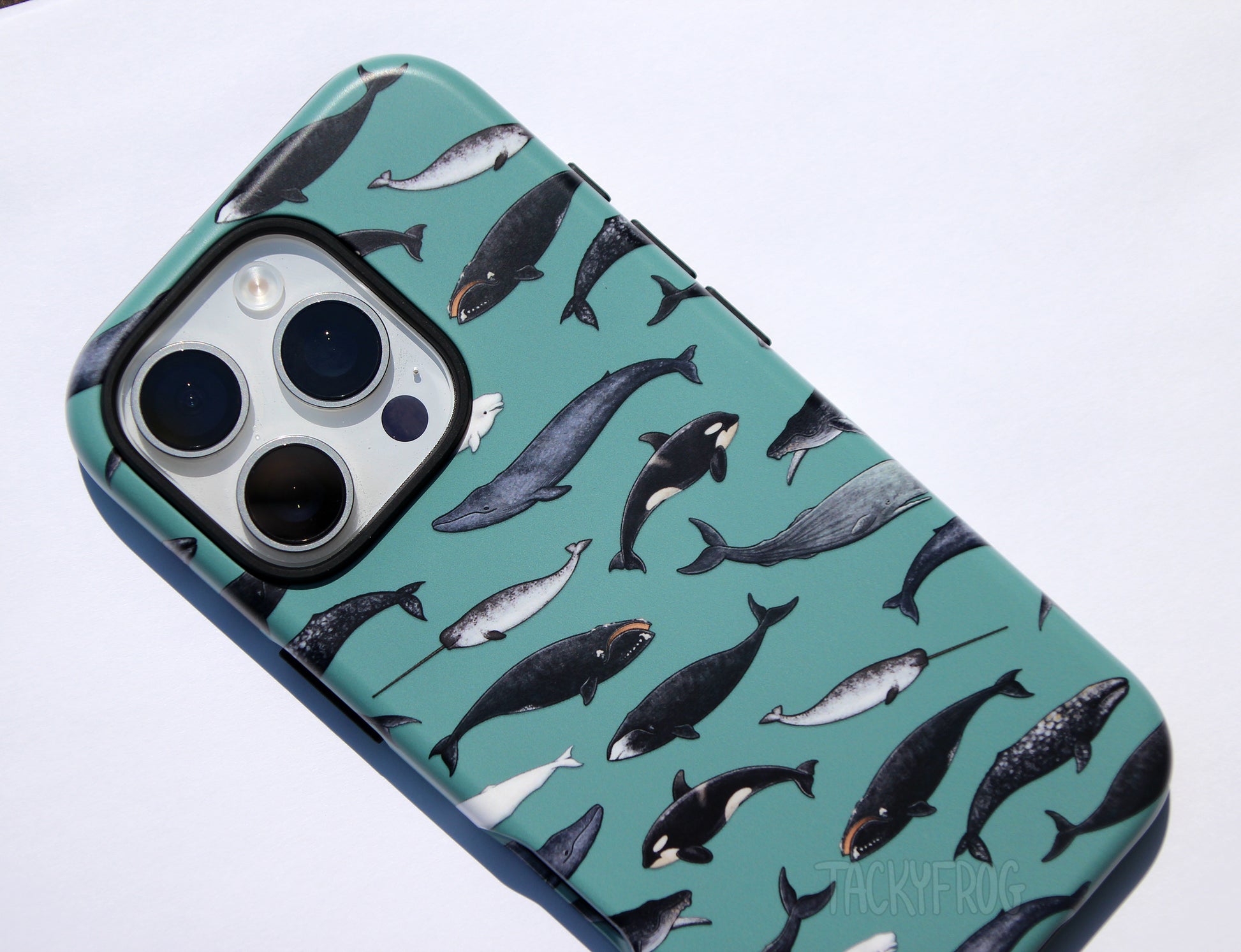 A close up of the whale phone case. There are nine species of whales depicted, including the humpback, orca, beluga, bowhead, and blue whale.