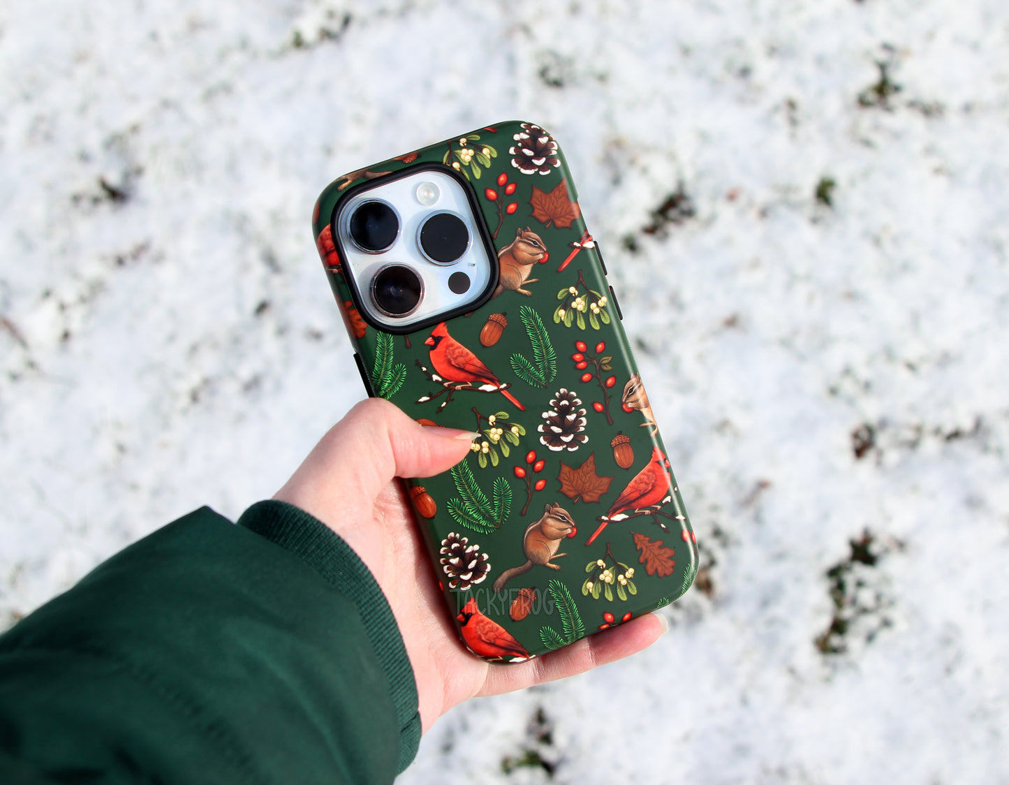 The winter hike-inspired phone case held above the snow.