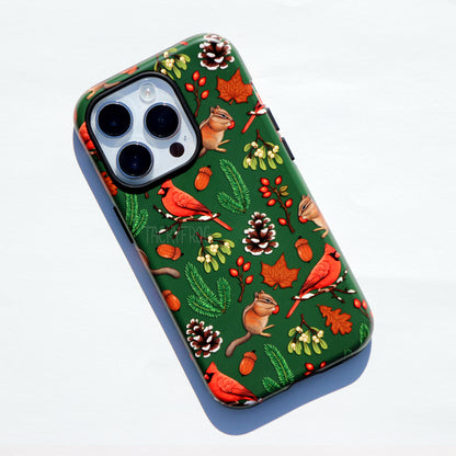 A green phone case featuring a pattern of various winter nature walk-inspired elements, including cardinals, chipmunks, rose hip, snowy pinecones, pine leaves, and more.