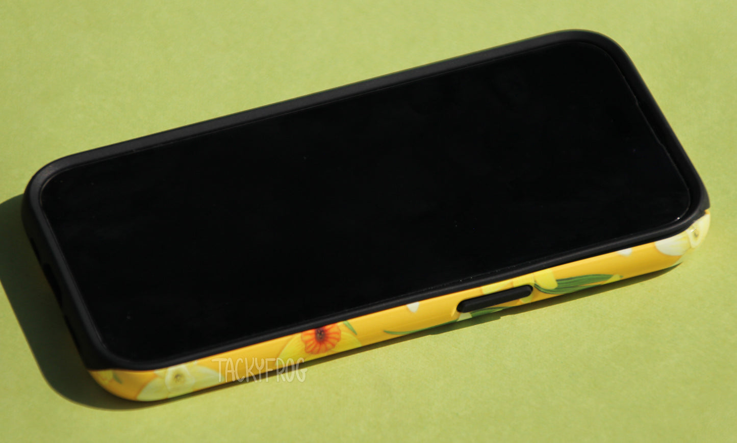 The yellow daffodils phone case shown screen-side up.