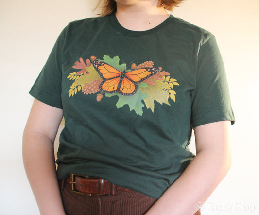 A forest green t-shirt with a monarch butterfly and autumn leaves on it.