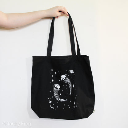 A black tote bag with a design depicting jellyfish in outer space on it.