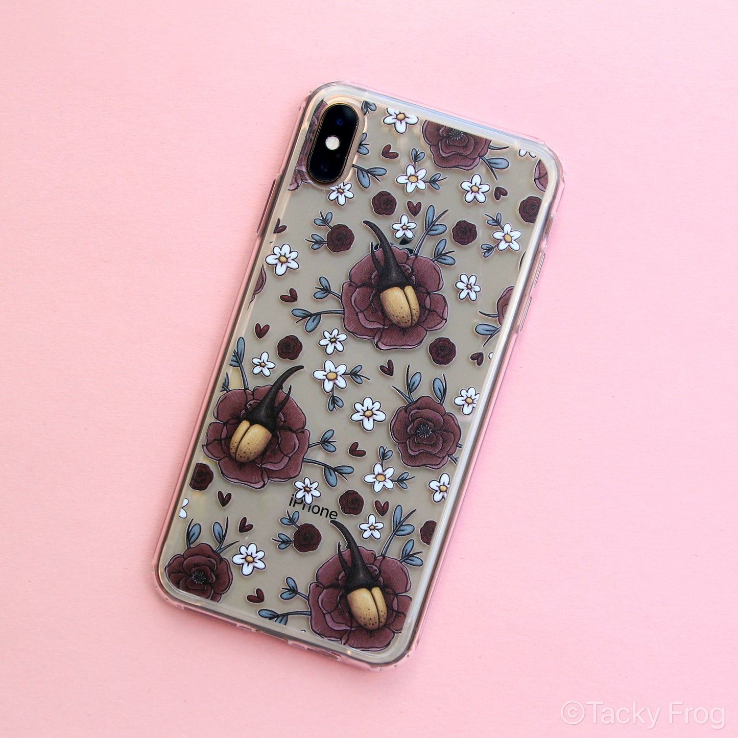 A clear phone case featuring a pattern of Hercules beetles, peonies, and daisies. It is shown on a gold iPhone.