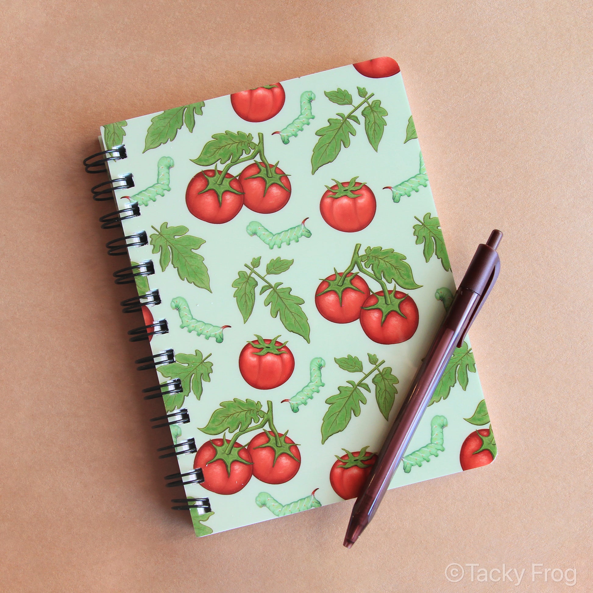 A 5 x 7 inch laminated notebook featuring a colorful pattern of tomatoes, leaves, and hornworm caterpillars on the cover.