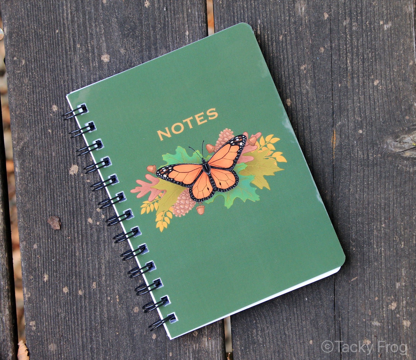 The monarch butterfly notebook placed on wooden planks.