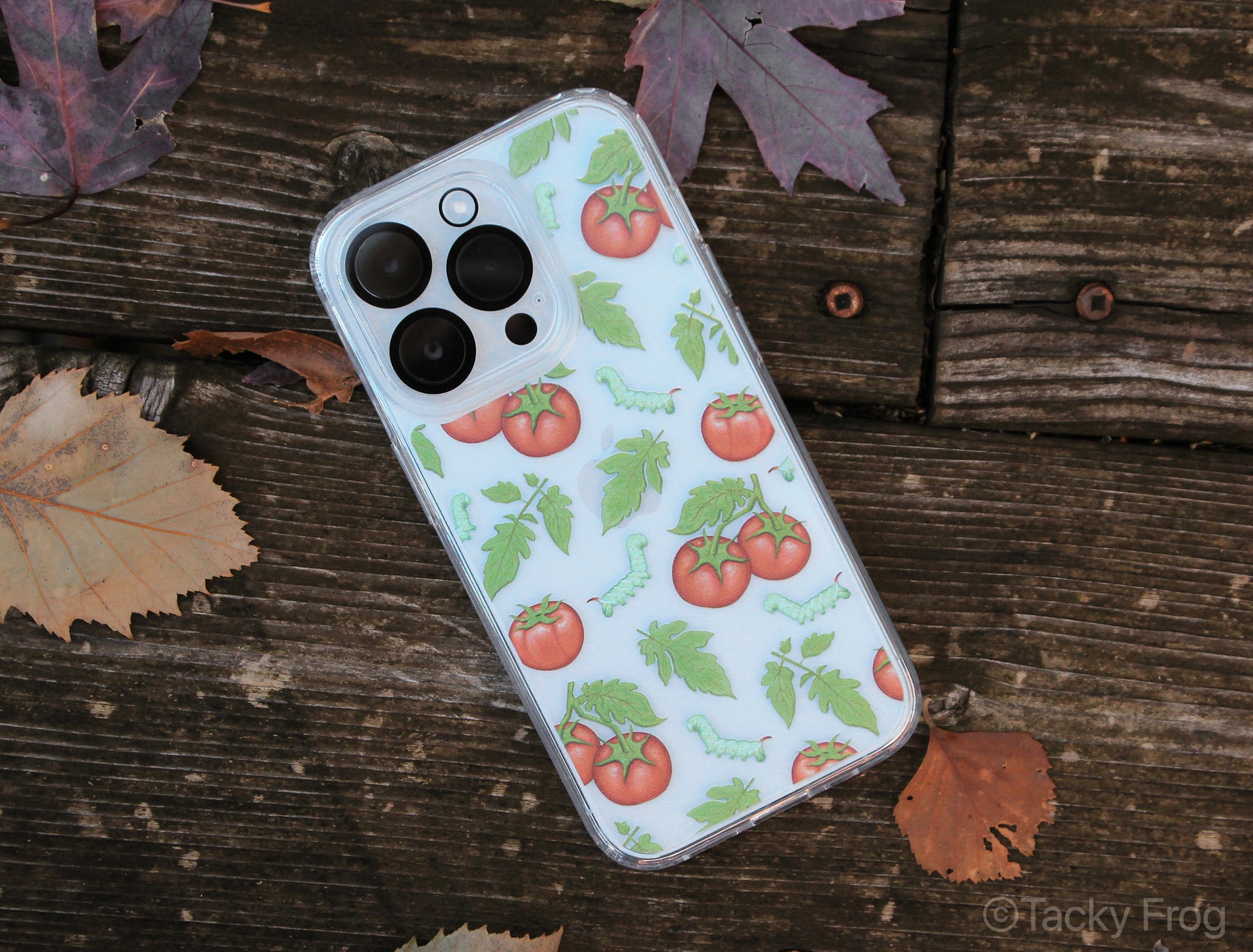 The clear tomato hornworm phone case next to some fallen leaves.