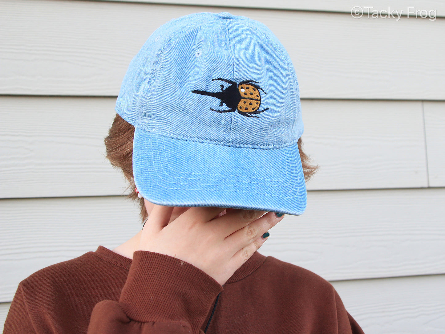 Another view of the Hercules beetle embroidered cap on a person.