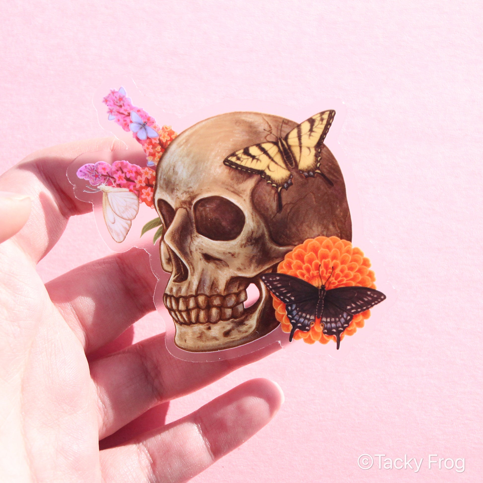 A clear vinyl sticker of a skull surrounded by flowers and butterflies.