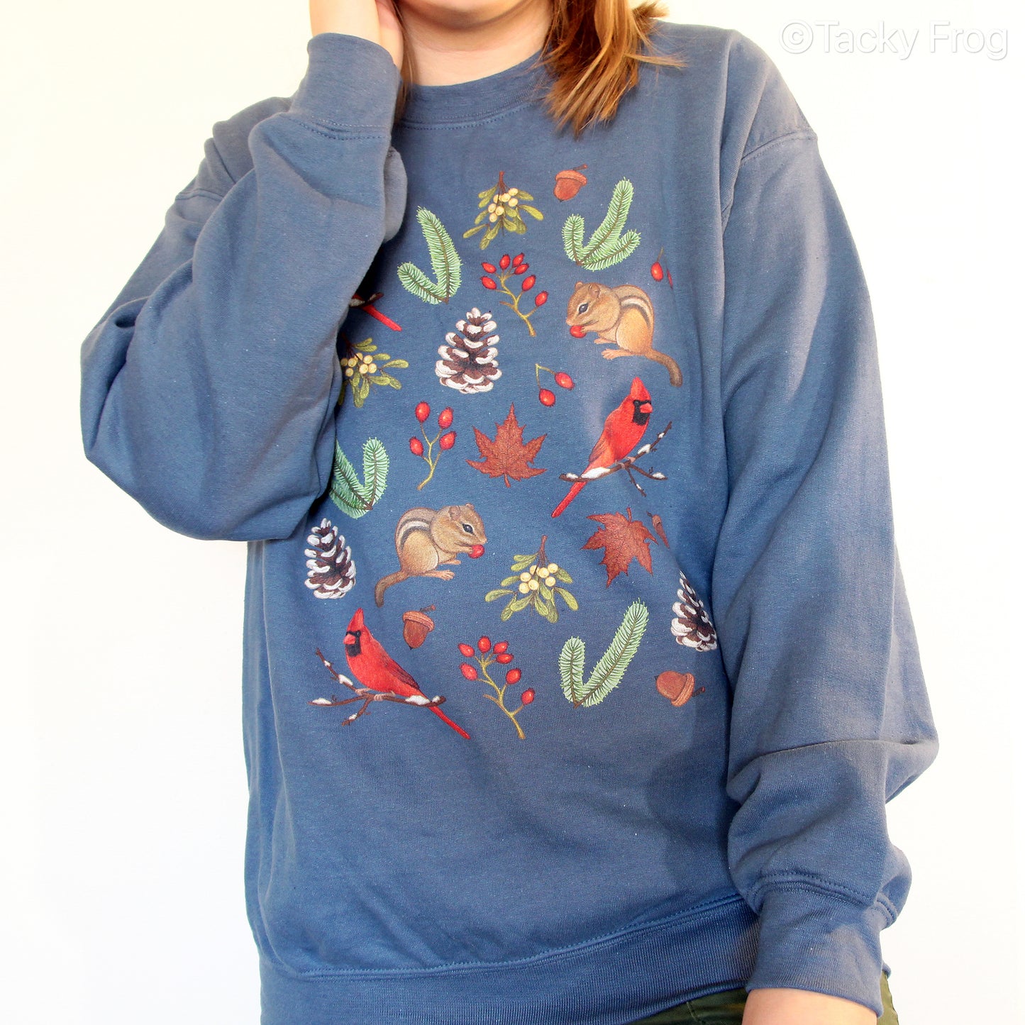 An indigo blue-colored unisex sweatshirt with various winter-inspired nature illustrations on it.