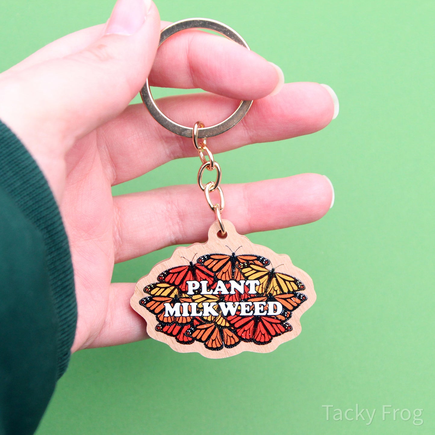 The plant milkweed keychain held in a hand. This provides a better view of the chain and key ring.